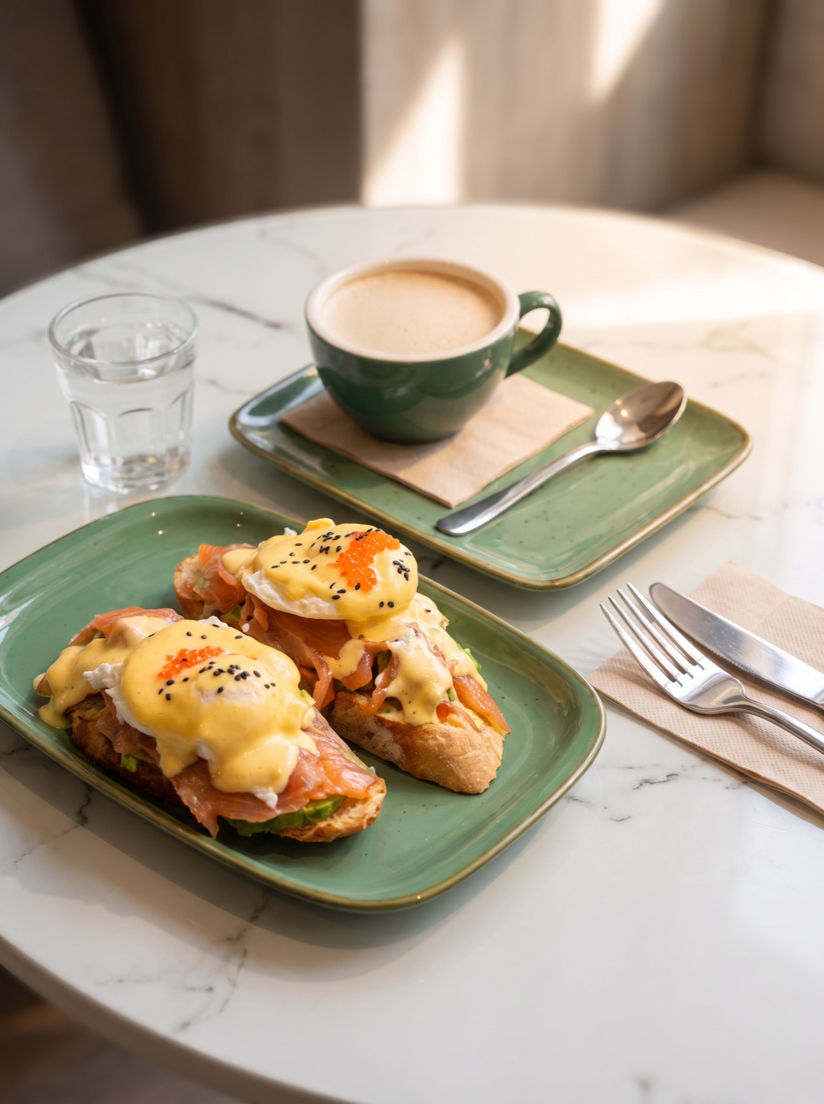 Huevos benedict y café con leche sobre una mesa de mármol