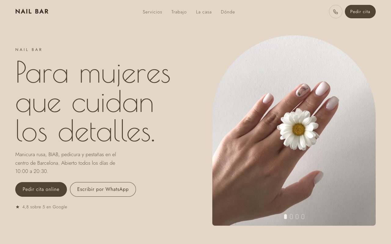 Web de un salón de uñas: mano con manicura blanca y una margarita, titular grande y botón de cita
